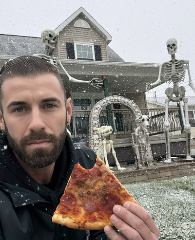 Evan Baker with a pizza and skeletons outside a home