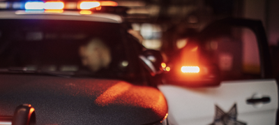 Close-up of a police patrol vehicle at night with emergency lights illuminated in red, blue, and amber.