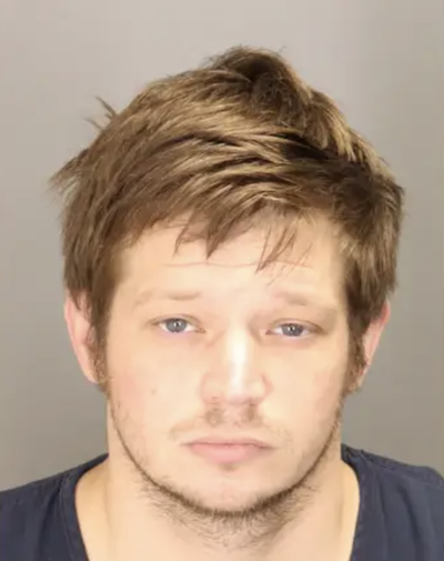 Booking photo of Jeremiah Bishop, a white man with brown hair, against a gray background.
