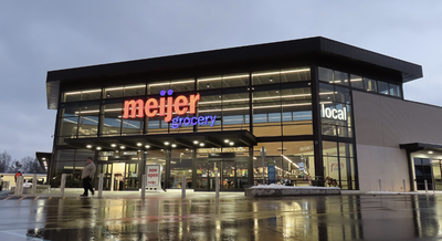 Exterior of a Meijer Grocery store at dusk, lit storefront with red "meijer" and blue "grocery" signage.