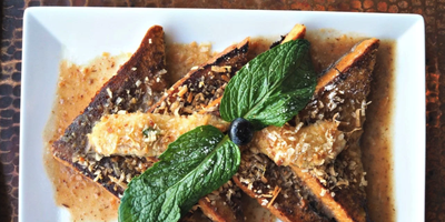 A plate of grilled French toast at Farm House Local, topped with toasted coconut, a fruit compote sauce, and fresh mint.